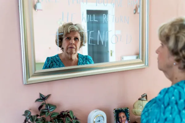 Ann lit des messages écrits sur un miroir chez lui avec une expression inquiète sur son visage