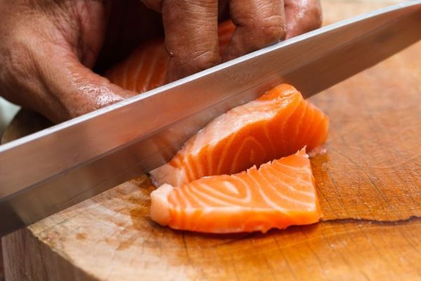 uomo che taglia salmone fresco con un coltello affilato