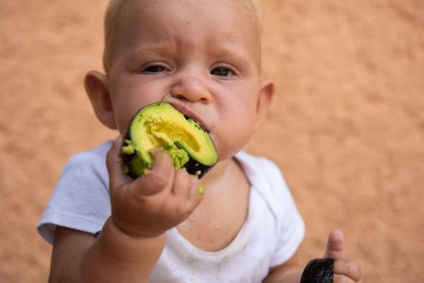 момченце, което яде авокадо с разхвърляни ръце
