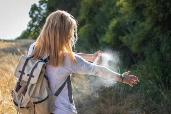 Turista che applica repellente per zanzare a portata di mano durante l'escursione nella natura. Repellente per insetti.