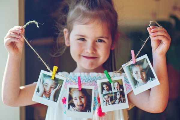 Vier jaar oud meisje met een reeks instantfoto's