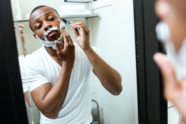 Portret przystojnego młodego czarnego mężczyzny do golenia w domowej łazience