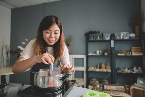 una artesana china asiática revolviendo y mezclando el ingrediente para hacer jabón casero