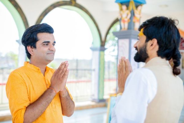 Visitante do templo e sacerdote hindu cumprimentando-se