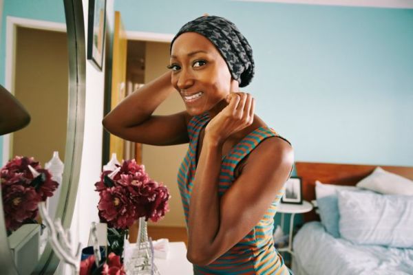 امرأة أمريكية من أصل أفريقي تبتسم واقفة في حجرة النوم