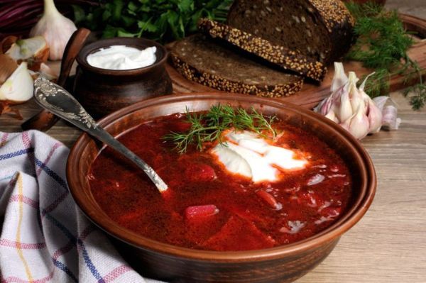 Zuppa di barbabietola borscht-vegetale, sul tavolo con fette di pane ai cereali di segale e panna acida
