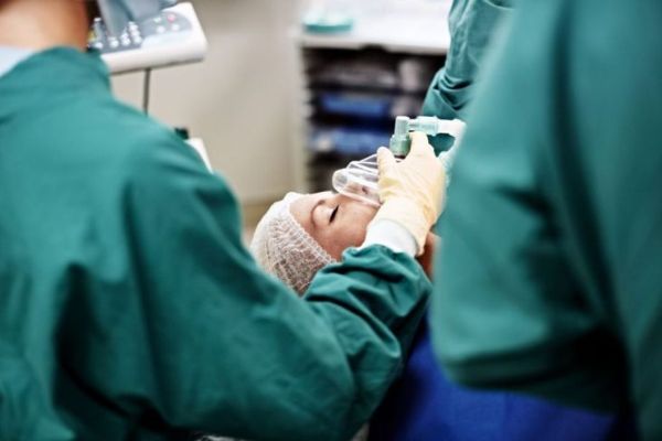 Кадър на анестезиолог и хирурзи, работещи върху пациент в операционна зала