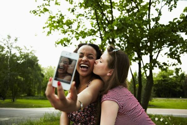 deux jeunes femmes adultes prenant un autoportrait avec un téléphone portable et s'amusant à faire des grimaces.