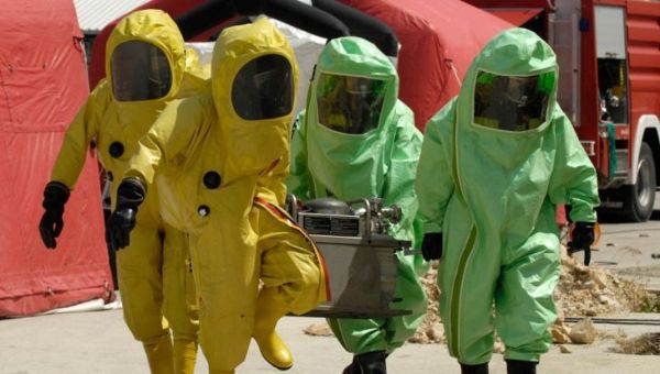Quatre agents de décontamination au travail en vert et jaune
