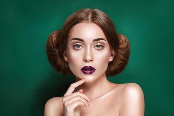 Jolie jeune femme mystérieuse avec un double chignon dans la coiffure de la princesse Leia regarde vers la caméra