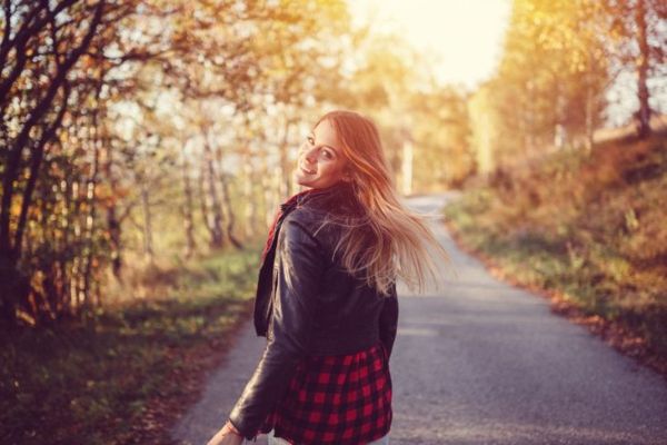 امرأة تبتسم تمشي على الطريق في الطبيعة
