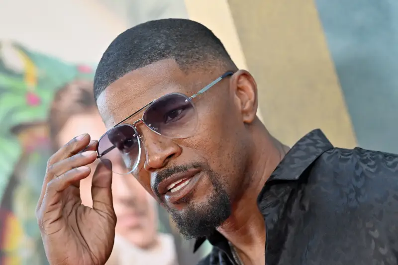 Un gros plan de Jamie Foxx. Il porte des lunettes de soleil et une chemise noire.