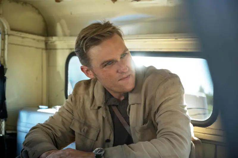 Wyatt Russell joue dans Monarch : Legacy of Monsters vêtu d'une veste marron, assis à l'arrière d'une camionnette